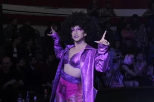 Mónica DiWhisky con peluca afro y vestuario estilo disco en morado